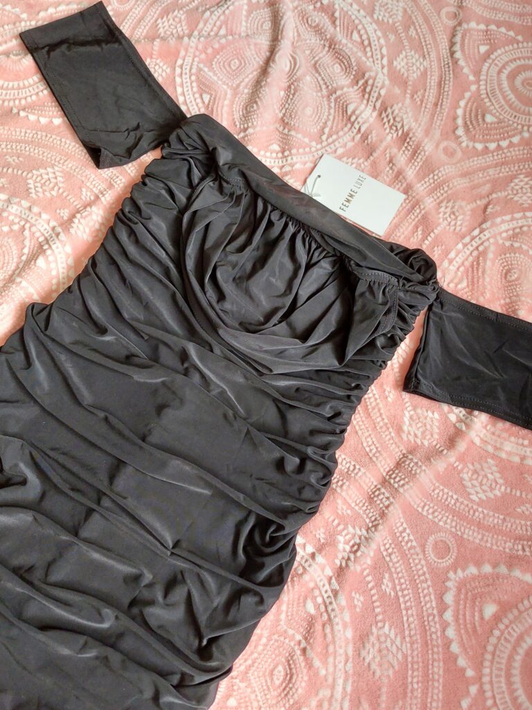 Black ruched dress laying on a pink blanket