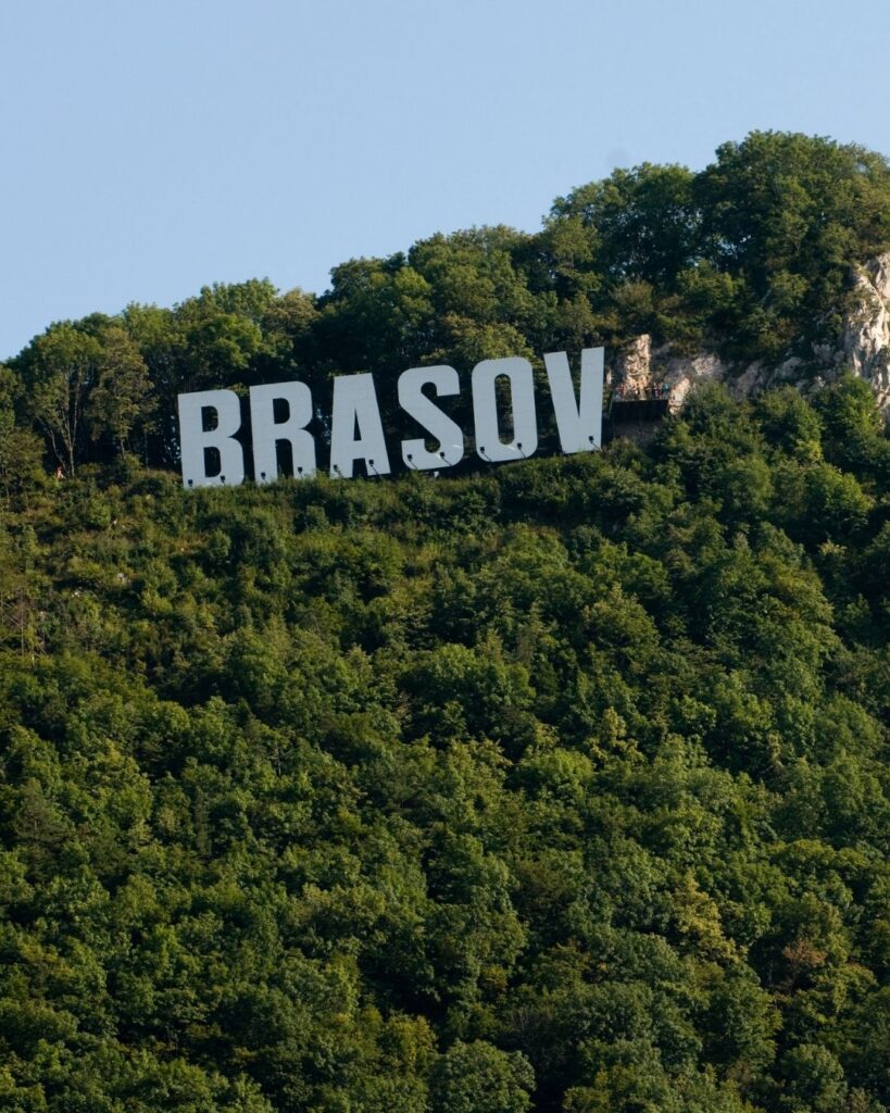 The Brasov sign surrounded by trees on the mountain.