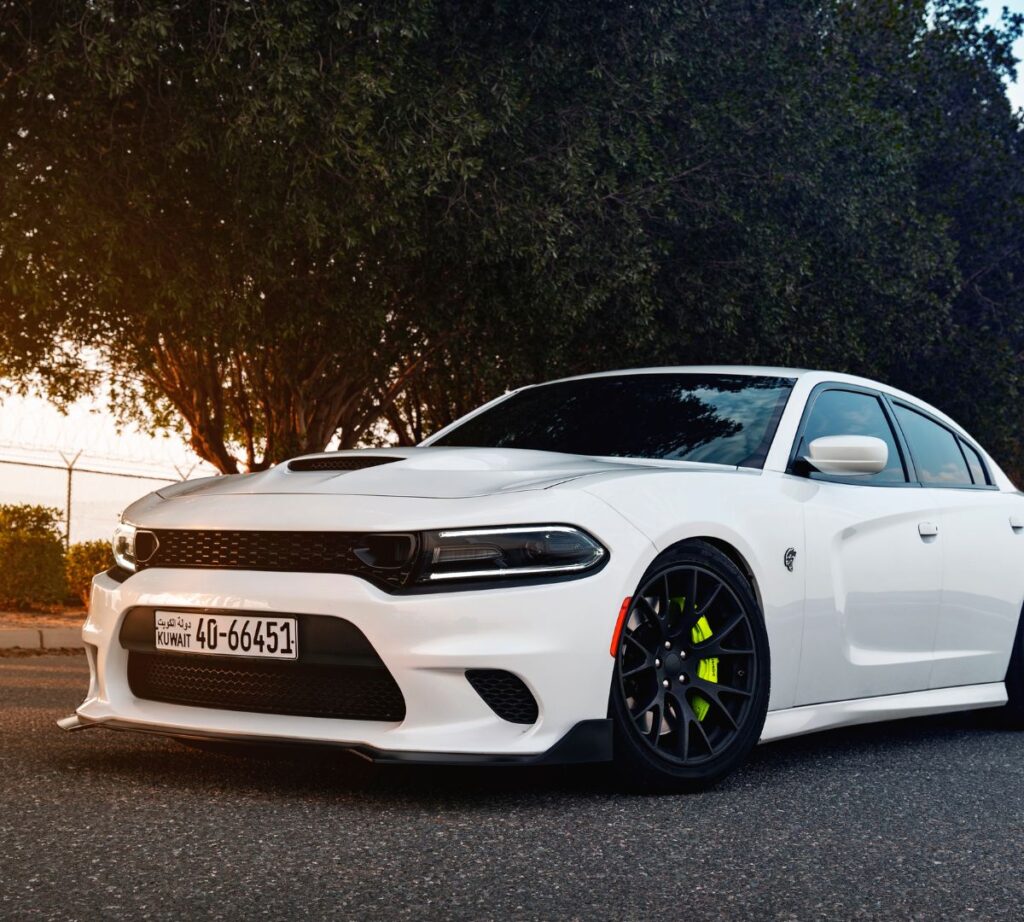 A white car with black wheels. a tree is in the background